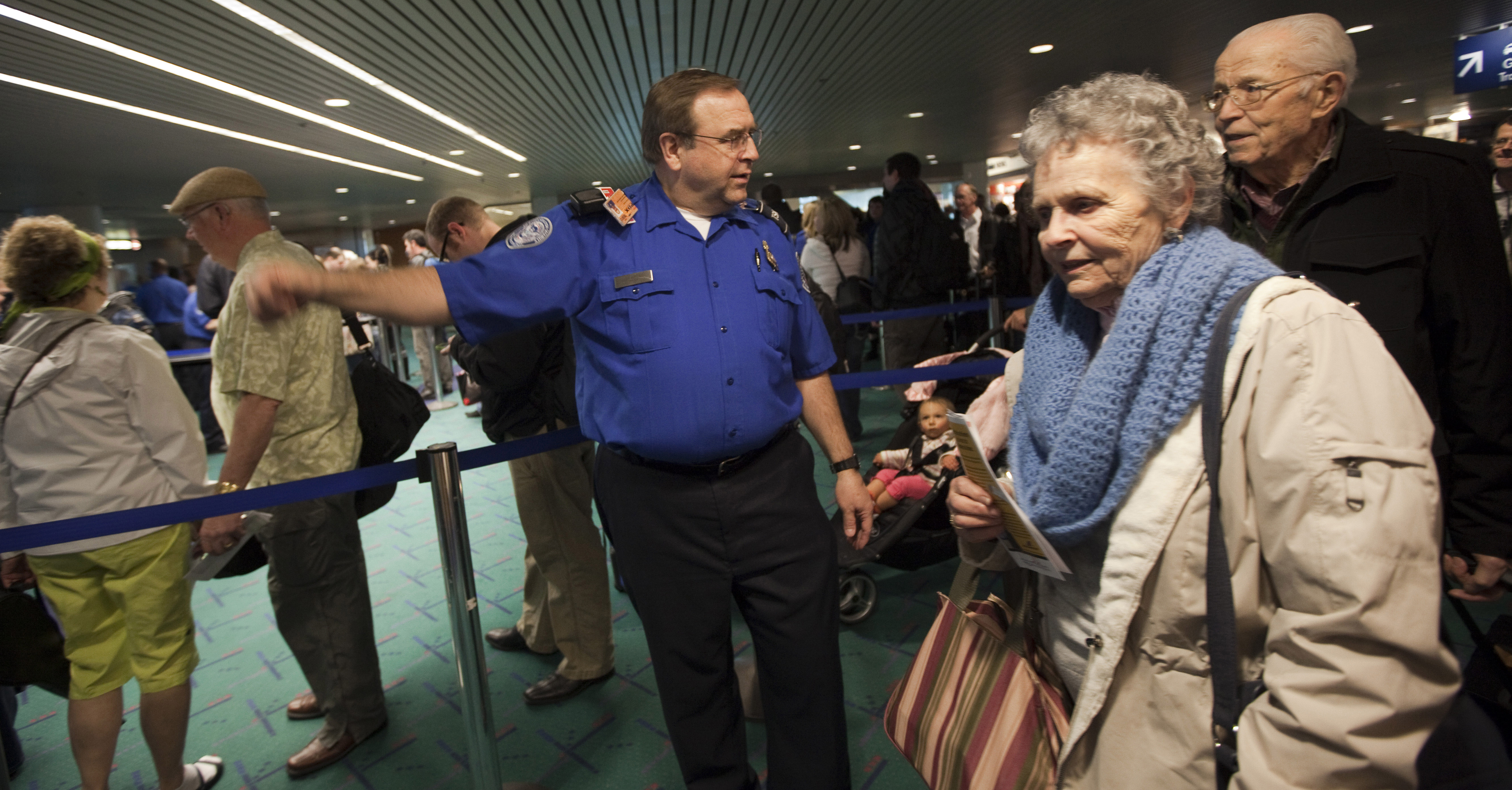 PORTLAND, OR - MARCH 19: A Transportation Security Administration (TSA) officer informs elderly travelers they can now leave their shoes and a light jacket on when passing through airport security at Portland International Airport (PDX) March 19, 2012 in Portland, Oregon. The TSA has modified screening procedures for passengers 75 and older and was implemented at four airports nationwide as a part of a pilot program. (Photo by Natalie Behring/Getty Images)
