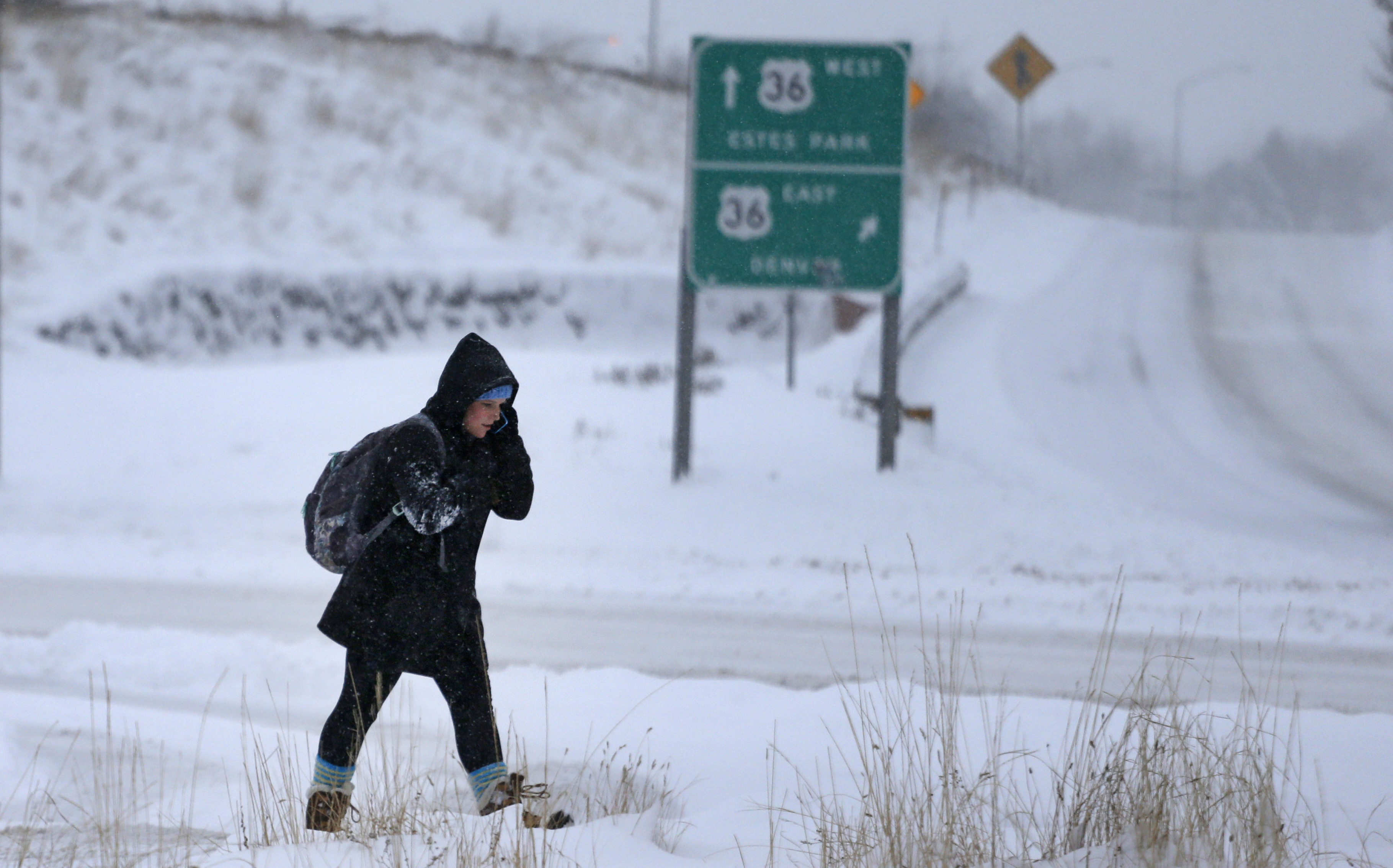 A pedestrian crosses a road after a night of heavy snowfall, in Boulder, Colo., Tuesday, Dec. 15, 2015. The biggest winter storm to hit the Denver area so far this season has left most schools closed and created some havoc on the roads for those forced to commute. (AP Photo/Brennan Linsley)