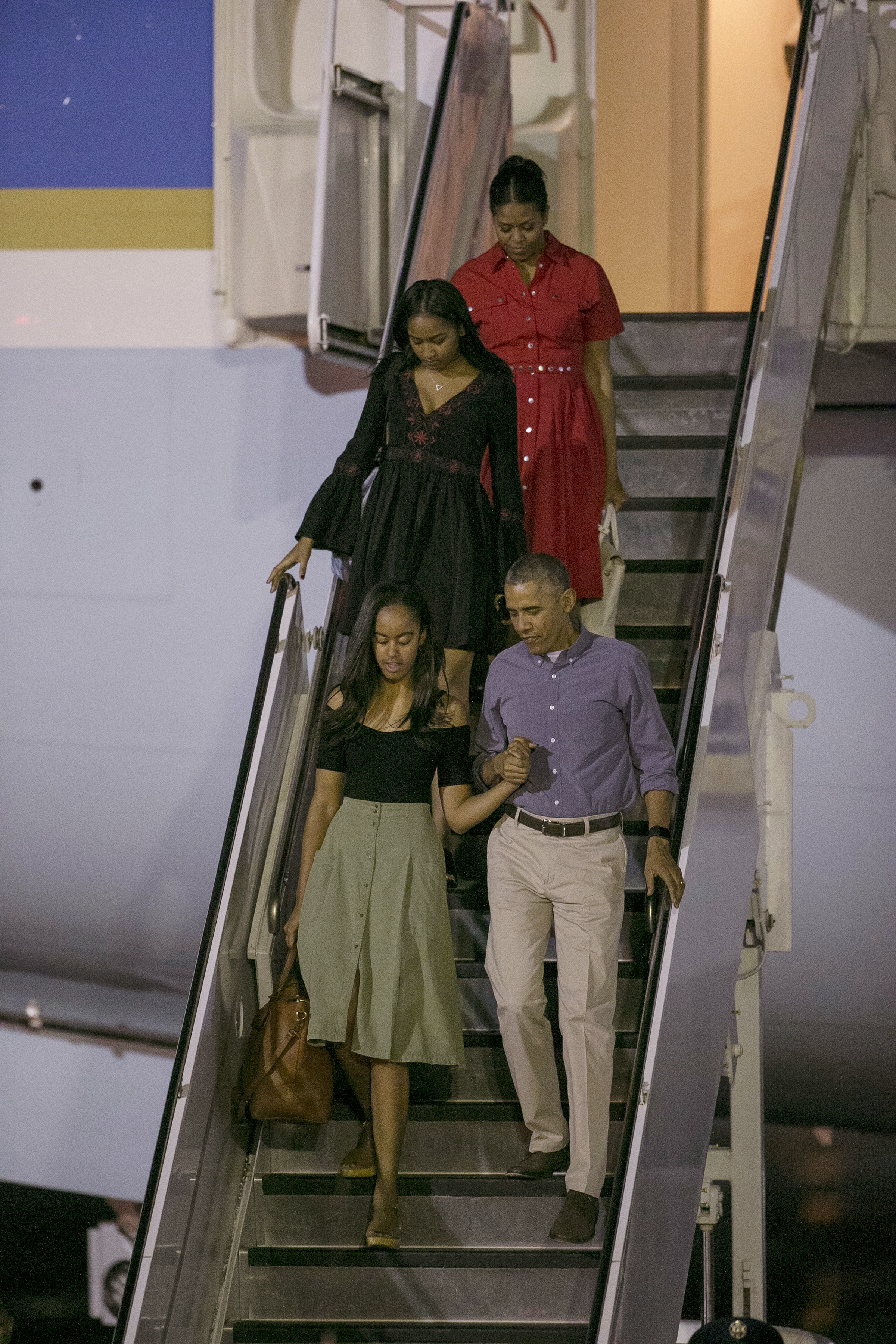 U.S. President Barack Obama, first lady Michelle, top, and their daughters, Malia Obama, bottom, and Sasha, exit Air Force One upon their arrival at Joint Base Pearl Harbor-Hickam, Friday, Dec. 16, 2016, in Honolulu, Hawaii, for their annual family vacation on the island of Oahu. (AP Photo/Marco Garcia)