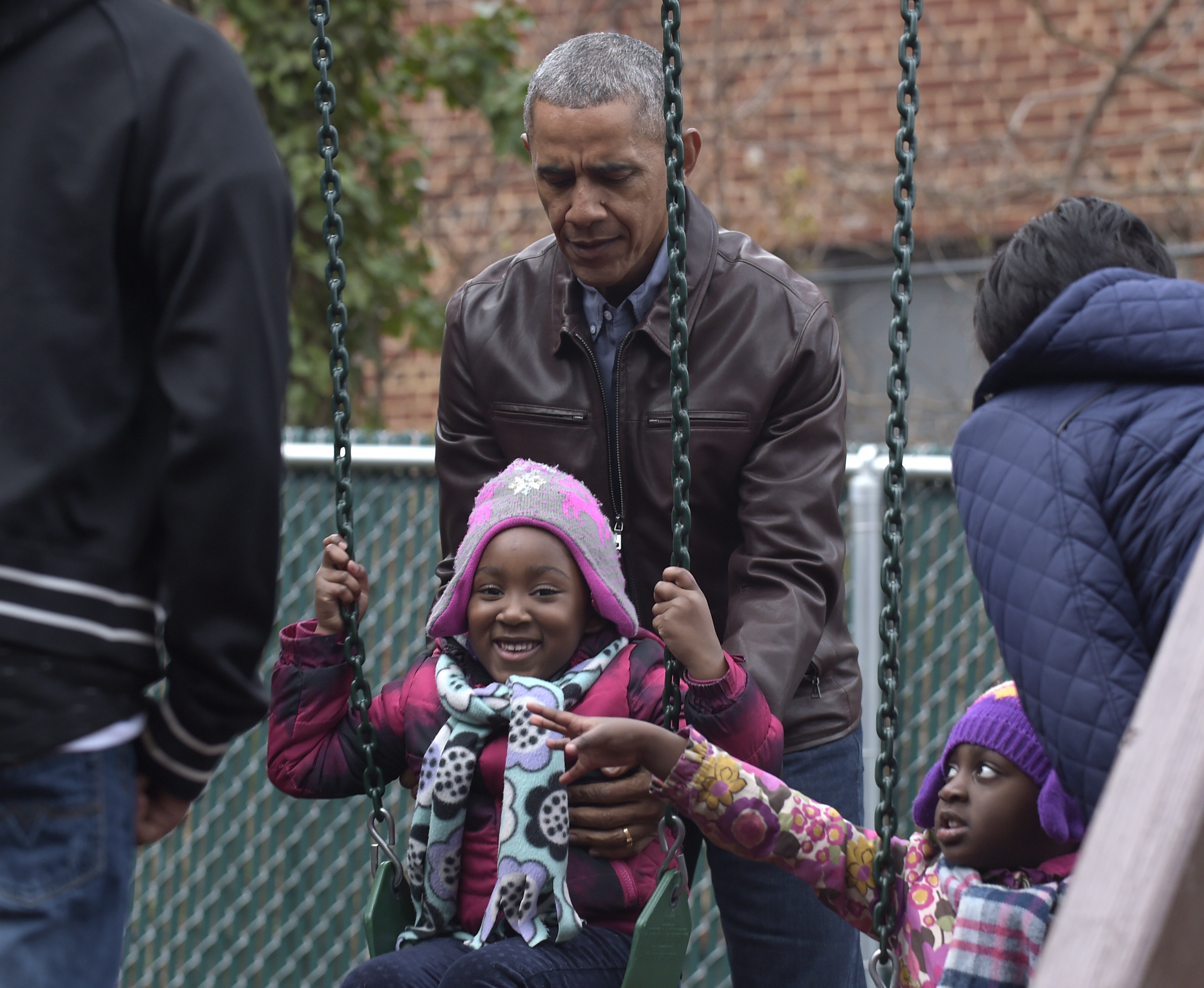President Barack Obama pushes kids on the swings as they visit "Malia and Sasha's Castle," the playground that the Obamas donated to the Jobs Have Priority Naylor Road Family Shelter in Washington, Monday, Jan. 16, 2017. (AP Photo/Susan Walsh)