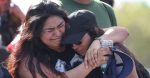 Fernanda Mora (L) an alumna from Deerfield Beach high school and Vallery Cruz a senior at the school hug in front of Marjory Stoneman Douglas High School after walking the 11 miles from school to school in support of the victims of the mass shooting on campus on February 23, 2018 in Parkland, Florida. Police arrested 19-year-old former student Nikolas Cruz for killing 17 people at the high school.