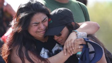 Fernanda Mora (L) an alumna from Deerfield Beach high school and Vallery Cruz a senior at the school hug in front of Marjory Stoneman Douglas High School after walking the 11 miles from school to school in support of the victims of the mass shooting on campus on February 23, 2018 in Parkland, Florida. Police arrested 19-year-old former student Nikolas Cruz for killing 17 people at the high school.