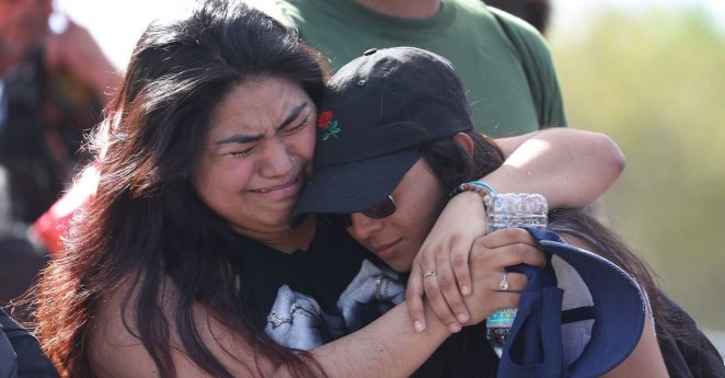 Fernanda Mora (L) an alumna from Deerfield Beach high school and Vallery Cruz a senior at the school hug in front of Marjory Stoneman Douglas High School after walking the 11 miles from school to school in support of the victims of the mass shooting on campus on February 23, 2018 in Parkland, Florida. Police arrested 19-year-old former student Nikolas Cruz for killing 17 people at the high school.