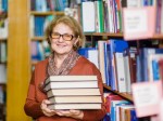 Happy senior woman with books in library